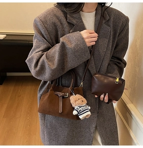 Detail of vintage brown suede bucket bag with leather buckle and teddy bear charm