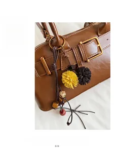 Detail of brown leather shell bag with gold buckle and fuzzy decorative charms