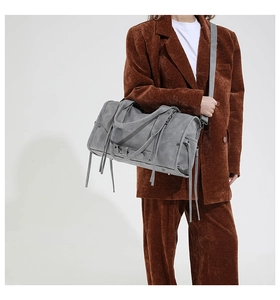 Sac à main Boston gris avec franges et rivets porté sur un costume en velours