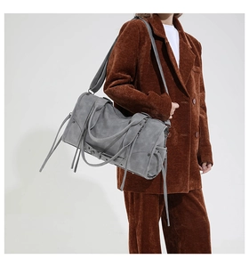 Gros plan du sac cabas en daim gris avec de longues franges et détails métalliques