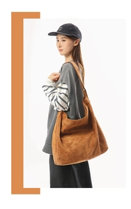 Grand sac hobo en daim marron porté par un mannequin dans un style minimaliste