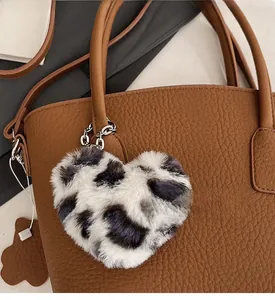 Close-up of heart-shaped leopard print plush charm attached to a brown leather handbag