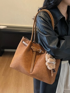 Brown woven leather tote bag with adjustable buckle and cute bear pendant on a model