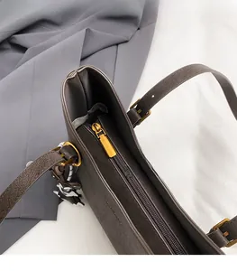 Detail of dark brown tote bag with gold zipper and adjustable strap on office fabric