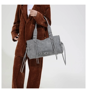 Détail d'un grand sac cabas gris avec de longues franges et des rivets sur cuir mat