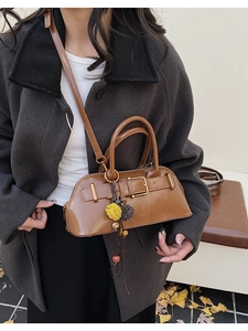 Close-up of brown leather shell bag with vintage metal buckle and floral charm details