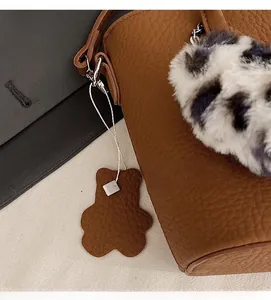 Detail of brown litchi pattern leather bag with leopard faux fur ball and bear charm