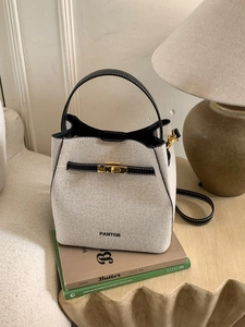 Contrast beige woven bucket bag with black leather trim and elegant gold twist lock