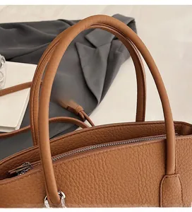 Detail of dark brown lychee pattern leather tote bag with sturdy handles and zipper