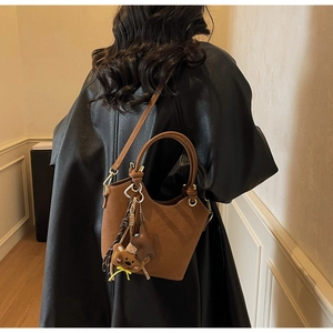 Brown bucket bag style shown on a model wearing a black coat for a trendy street look