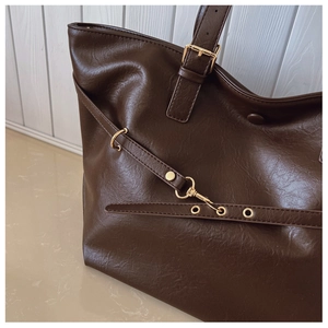 Dettaglio della borsa tote marrone scuro con trama in pelle e finiture in metallo oro