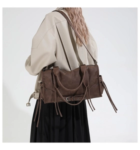 Détail du grand sac cabas rétro marron foncé avec pompons à franges et boucle de style moto