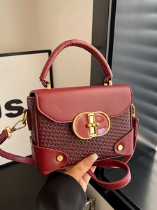 Burgundy woven leather crossbody bag with golden oval buckle and top handle