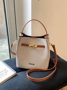 Contrast color bucket bag in beige canvas and brown leather with gold clasp closure