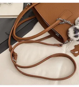 Brown lychee leather tote bag featuring a leopard fur ball charm and silver chain detail