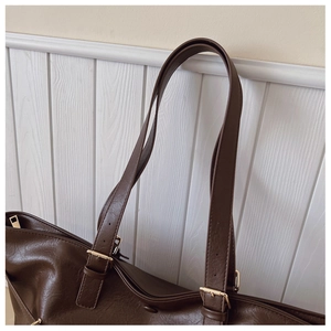 Dettaglio della borsa tote in pelle PU marrone scuro con spalline e fibbie dorate