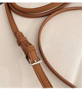 Close-up of brown lychee grain leather strap with silver metal buckle on shoulder bag