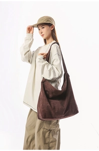 Détail d'un grand sac cabas en daim marron foncé avec une forme de demi-lune minimaliste