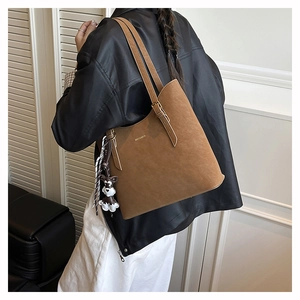 Brown suede tote bag detail with metal buckle and cute dog charm on model's shoulder