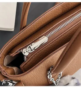 Detail of caramel lychee grain leather bag with smooth silver zipper and plush charm