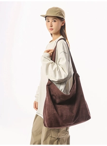 Vue latérale du grand sac hobo en daim marron foncé porté pour un style décontracté