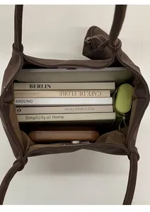 Top view of spacious brown tote interior with books, an umbrella, and a zipper pocket