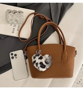 Detailed view of brown litchi grain handbag with leopard print heart plush charm decoration