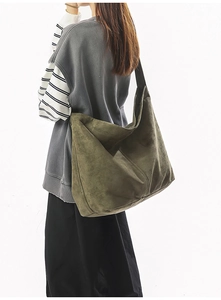 Détail d'un sac hobo en daim vert olive avec une large bandoulière noire pour femme