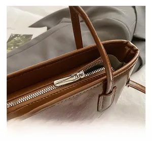 Detail shot of smooth silver metal zipper and neat stitching on brown retro bucket bag