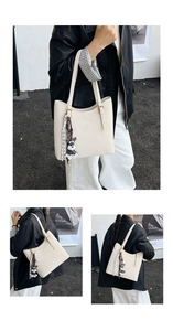 Detail of off-white tote bag featuring a cute schnauzer plush charm and golden logo