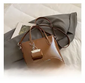 Close-up of dark brown glossy leather bucket bag featuring silver hardware and a mini pouch