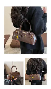Detail of dark brown vintage shell bag with glossy leather and tassel charm