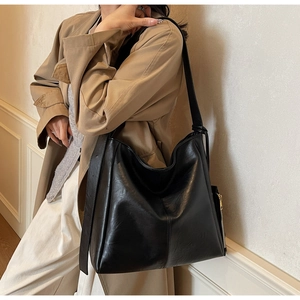 Detail of a large black leather hobo bag with a wide strap and metallic side zipper