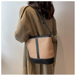 Close-up of stylish retro bucket bag with brown canvas and black leather stitching detail