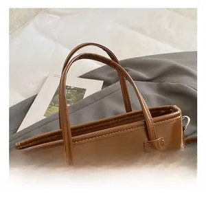 Close-up of comfortable double handles and high-gloss oil wax finish on the brown bucket bag