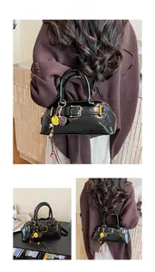 Detail of vintage black shell bag with glossy finish, gold buckle and colorful fur pompom