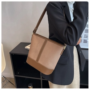 Detail of khaki canvas bucket bag with brown leather trim and white stitching