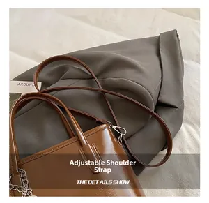 Detail showing the adjustable shoulder strap and glossy brown leather texture of the bag