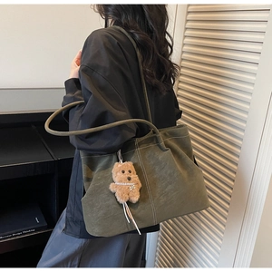 Detail of olive green tote bag with contrast stitching and plush dog charm