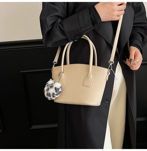 Close-up of apricot lychee pattern leather handbag with leopard print plush charm detail