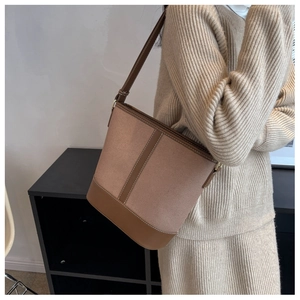 Detail of a contrast stitching canvas bucket bag with adjustable leather shoulder strap