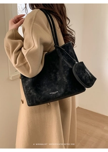 Detail of black suede tote bag with round coin purse and fashion logo on model