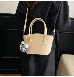 Detail of beige grainy leather bag with leopard heart charm and adjustable shoulder strap
