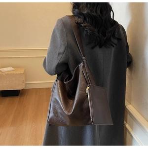 Detail of dark brown hobo shoulder bag featuring a matching small zip pouch on the strap