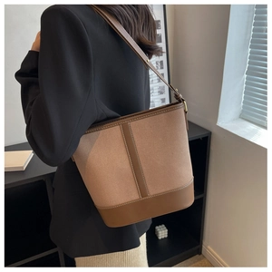Detail of canvas and leather patchwork bucket bag with visible white stitching