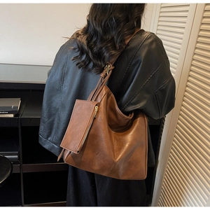 Detail view of brown leather tote bag with matching zipper pouch on model back