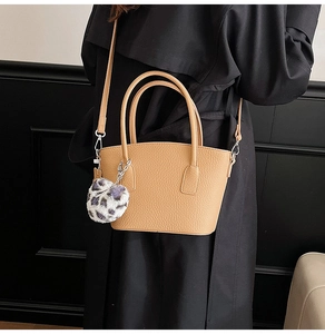Detail of camel leather bucket bag with litchi texture and leopard plush charm
