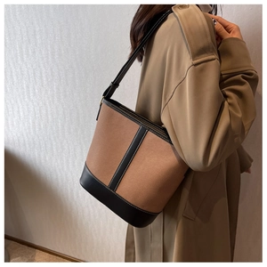 Detail of canvas bucket bag with black leather trim worn with a khaki trench coat