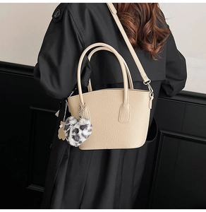 Detailed view of a beige hobo bag featuring a heart-shaped leopard print plush charm