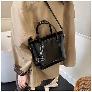 Detail of glossy black vintage bucket bag featuring a signature mini lock coin purse charm